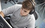 College aged student wearing headphones looking at a computer monitor 